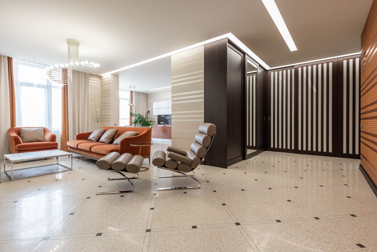 Interior of modern flat with spacious corridor and comfortable seats in living room with kitchen counter in distance at home