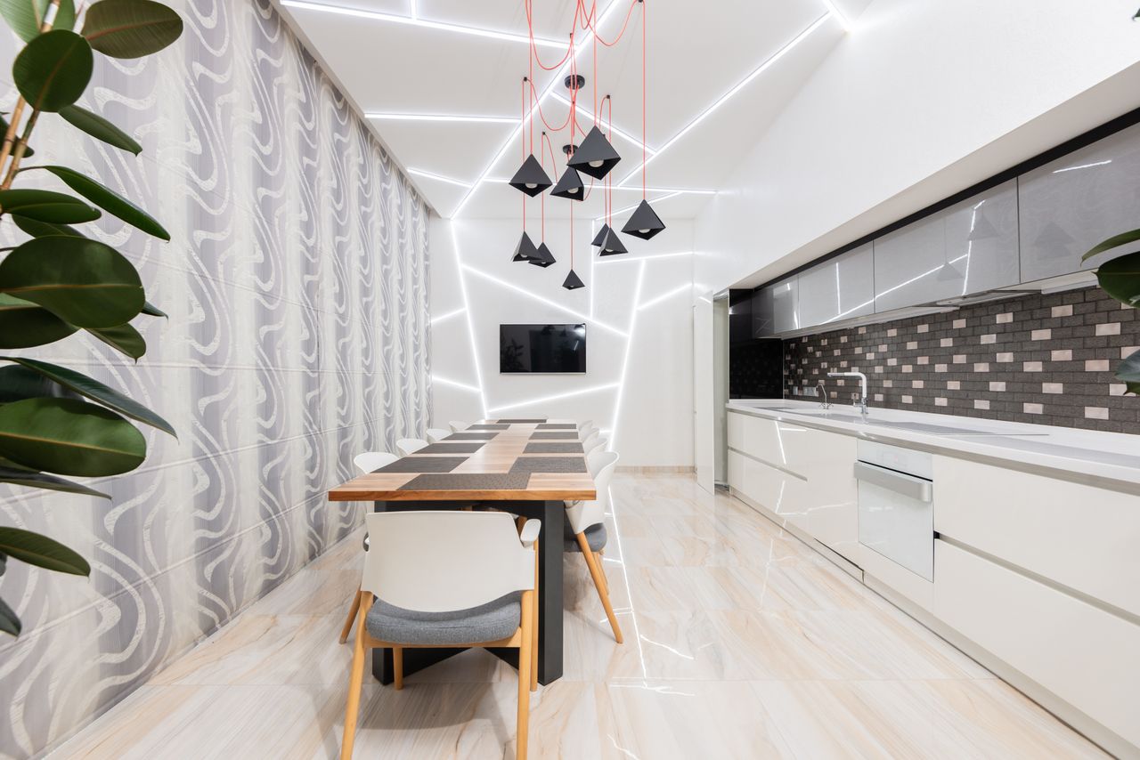 Offerings Wooden dining table and comfortable chair in spacious kitchen with white minimalist furniture and creative lamps